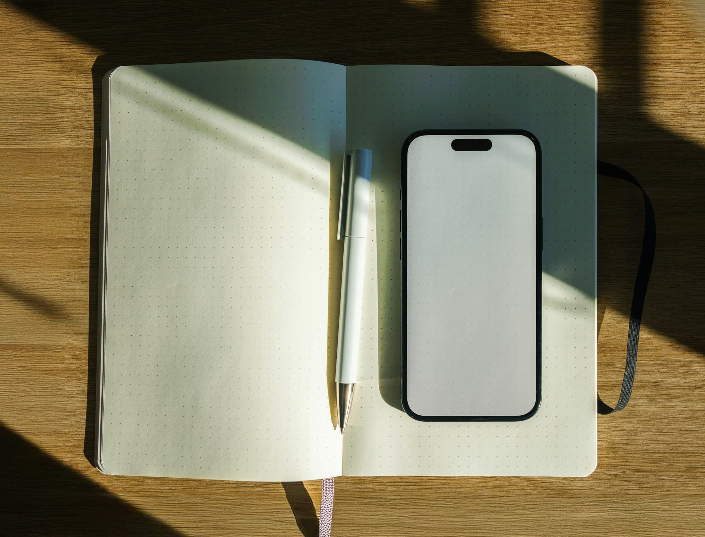 An open notebook, pen and phone in a patch of sunlight