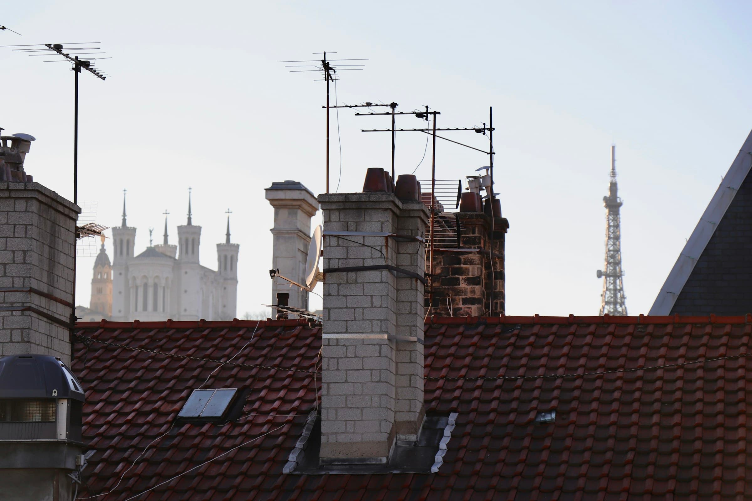Rooftop chimneys and antennas with a tower beyond
