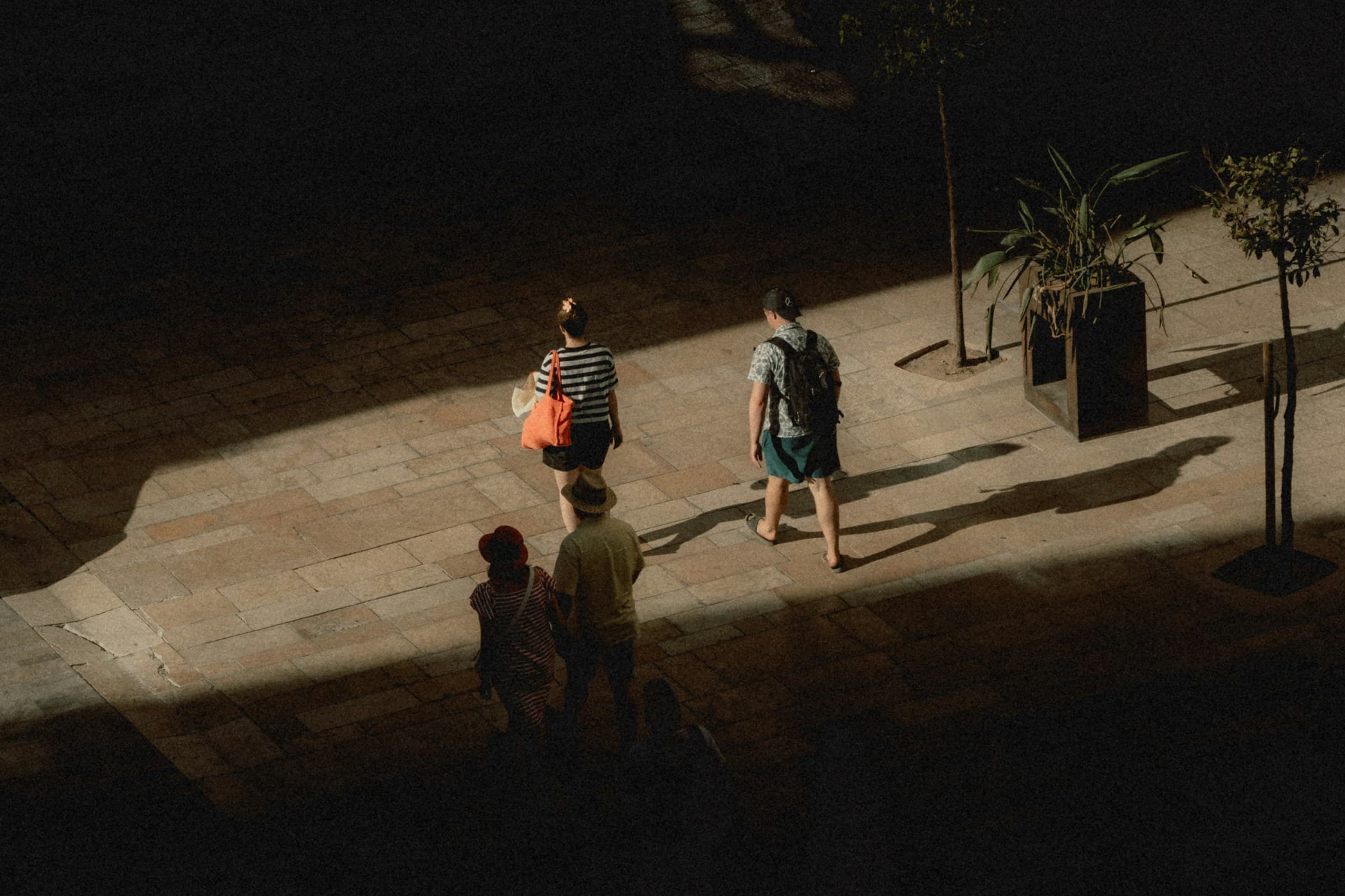 People crossing a plaza in low sun, seen from above