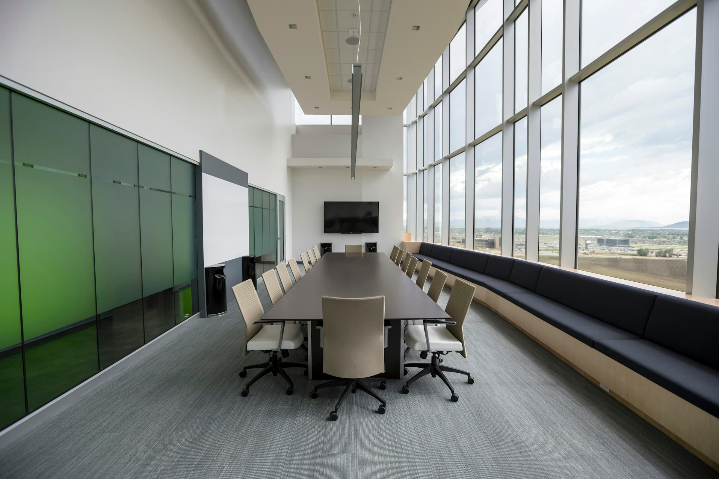 A long meeting table beside tall windows