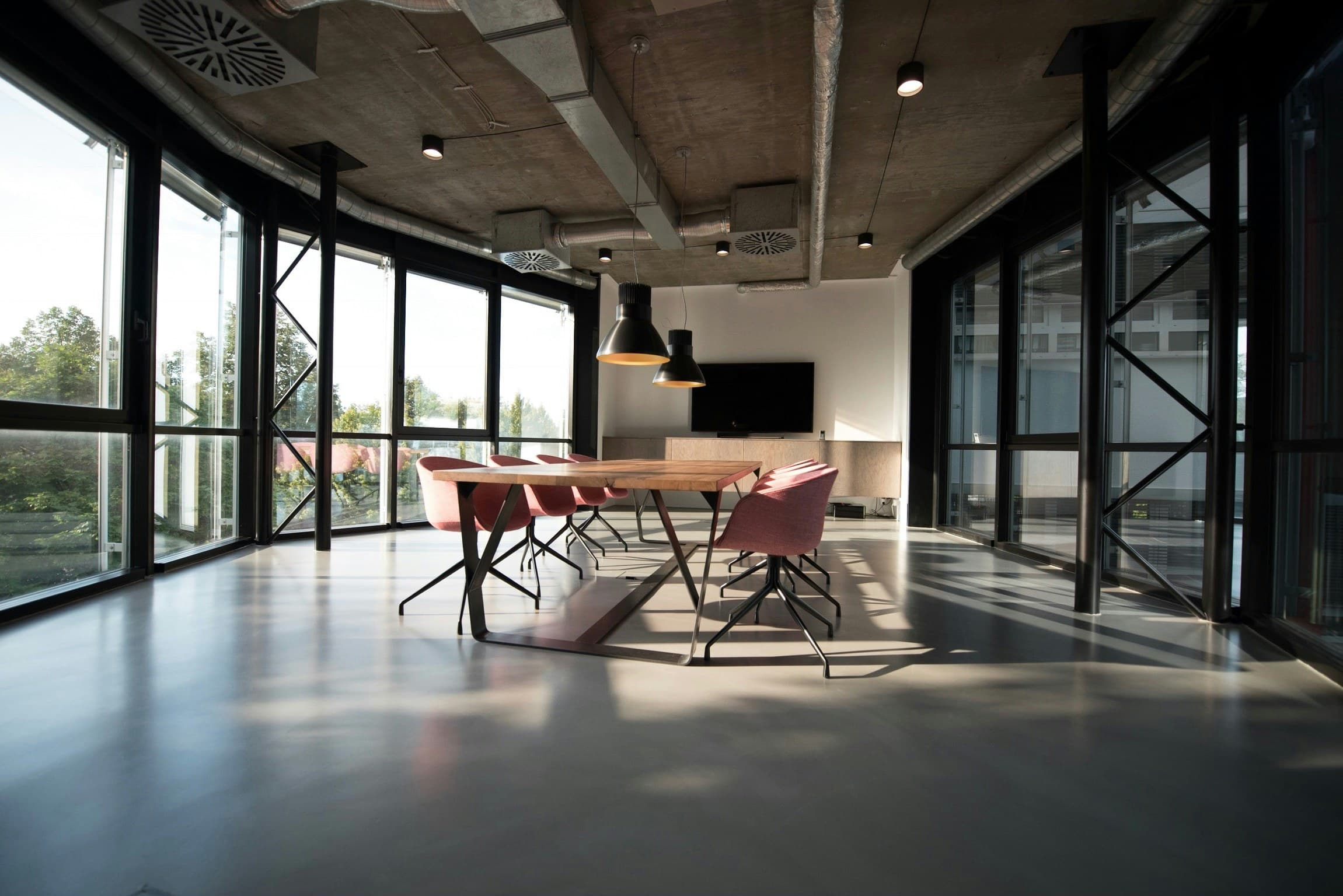 An empty meeting room with a long table and floor-to-ceiling glass