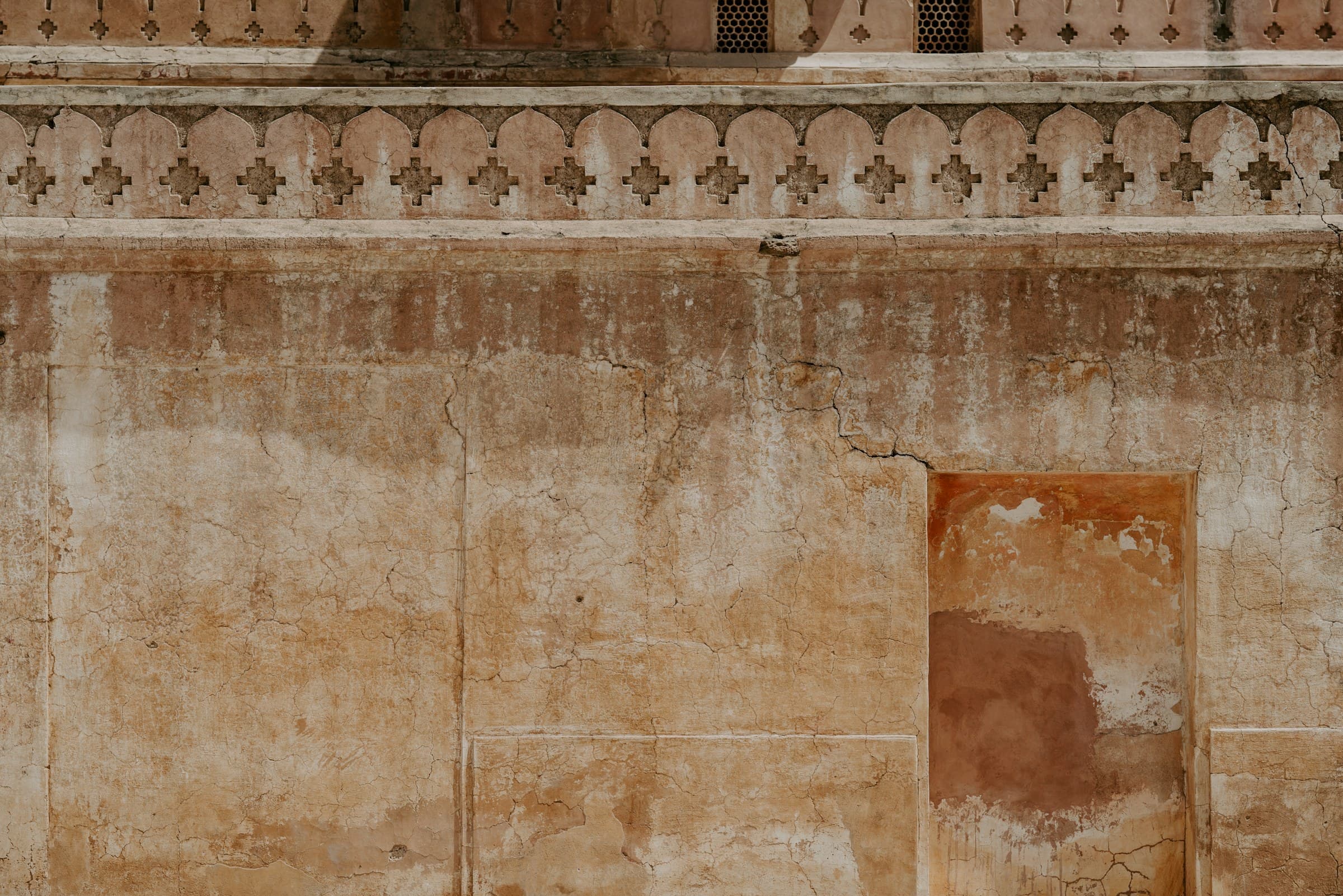 An ochre rendered wall with faded panels