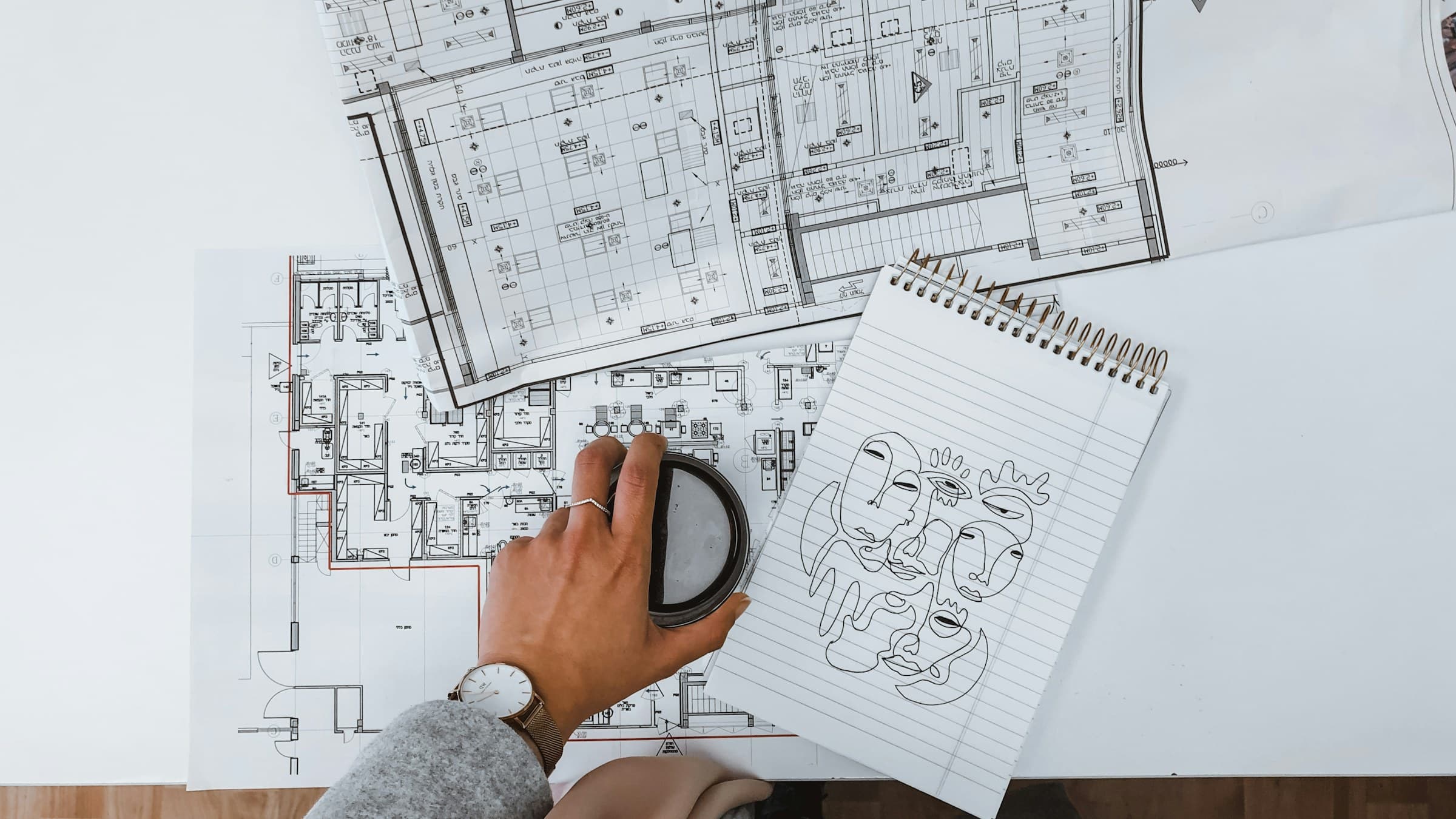 A hand over floor plans beside a notebook