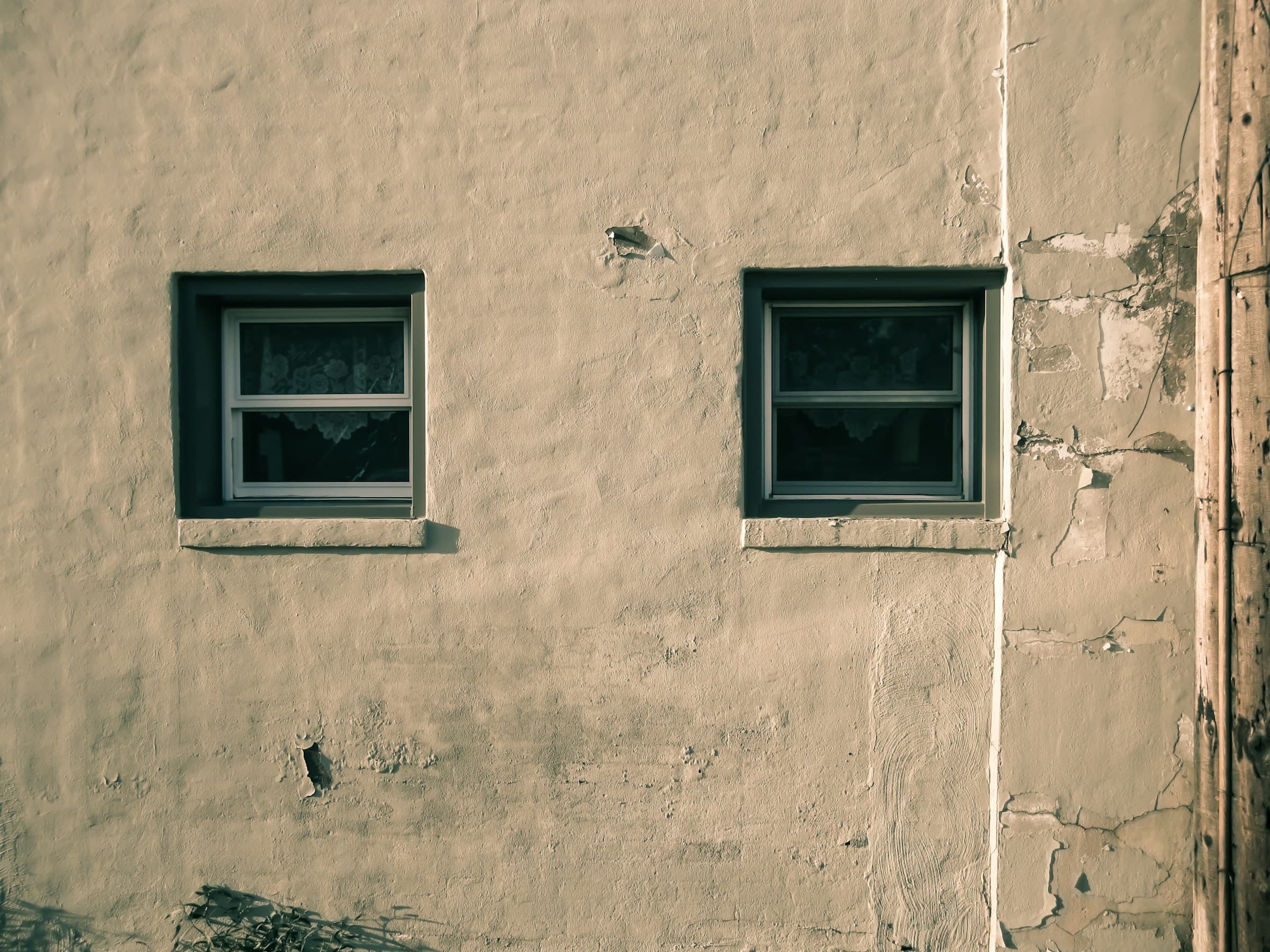 A beige plaster wall with two small windows