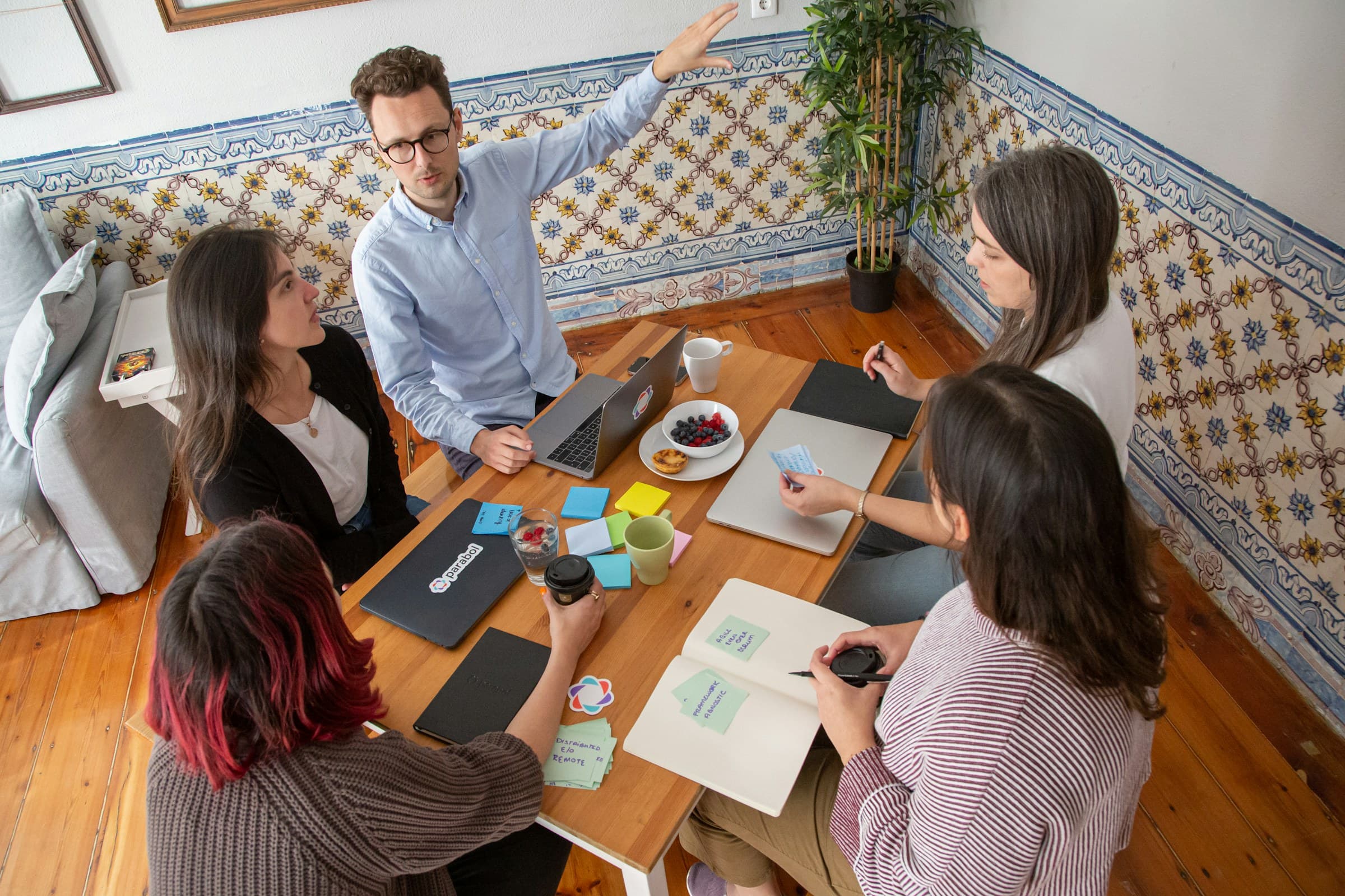 A team working around a table beside a tiled wall, seen from above