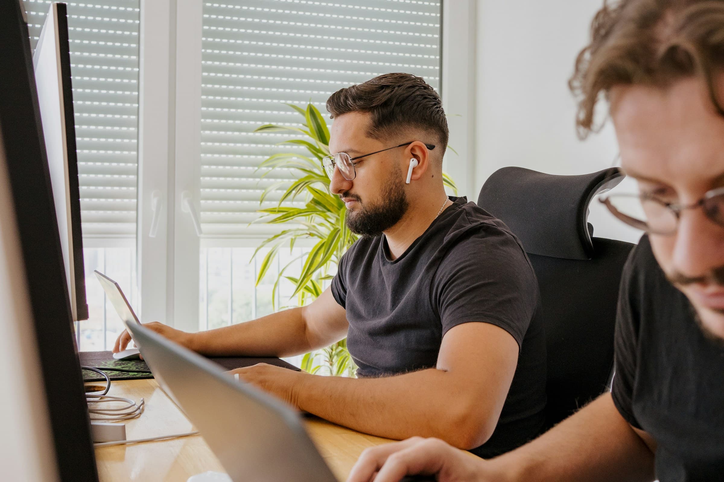 Two men at a desk looking at a laptop