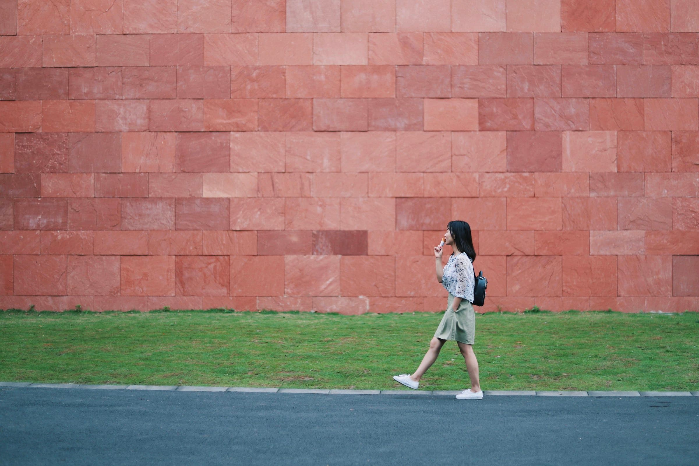 A person walking along a red stone wall