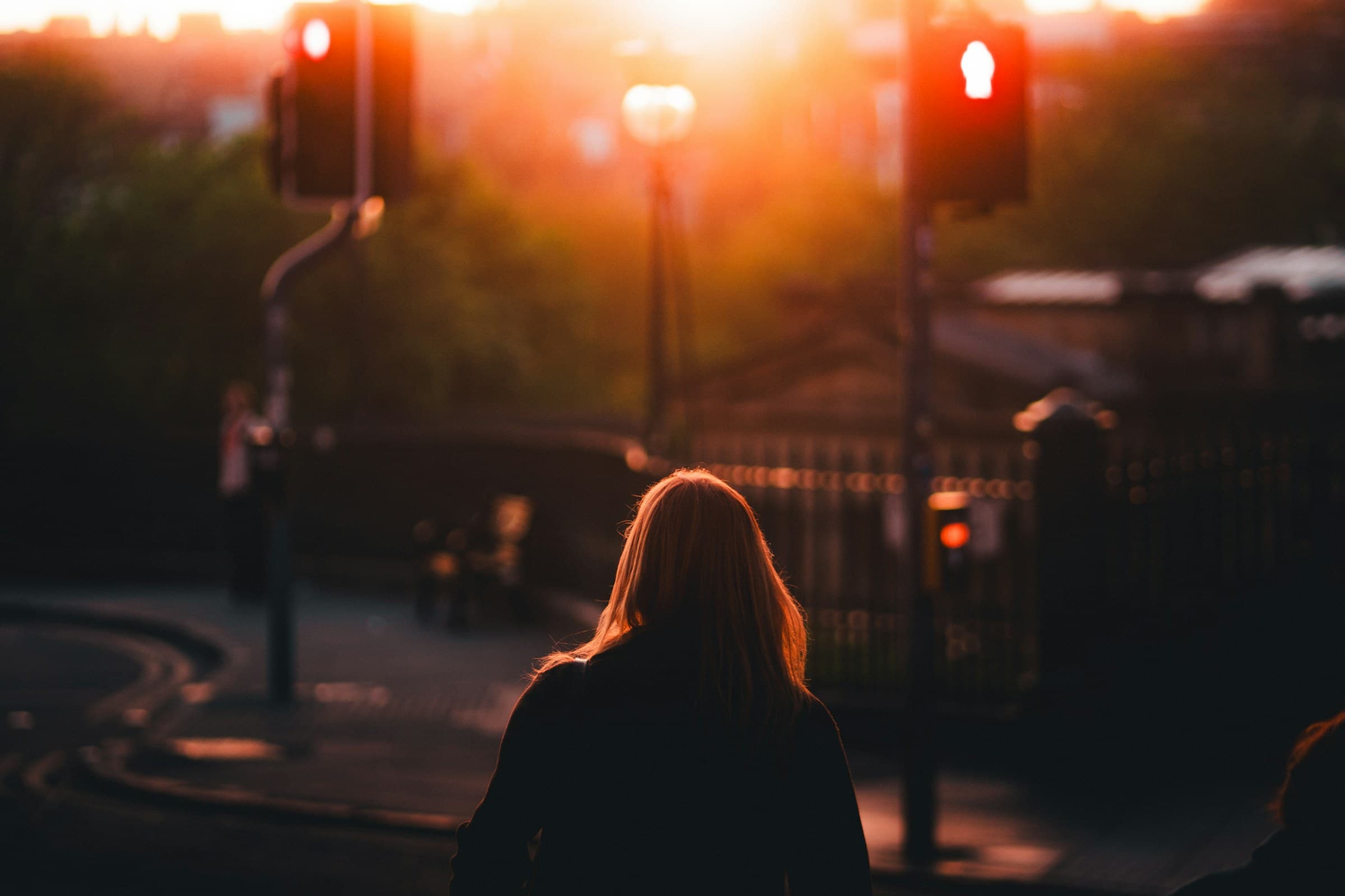 A woman at a crossing in warm evening glow