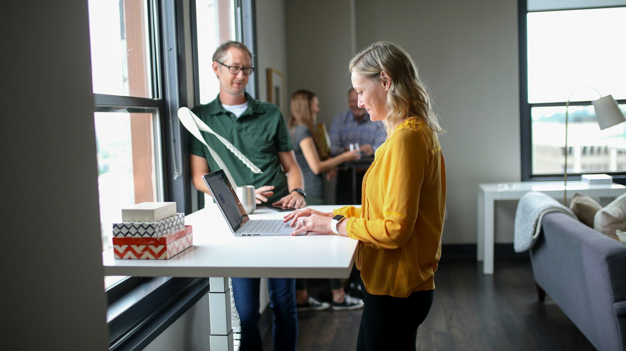 Two colleagues at a standing desk by a window
